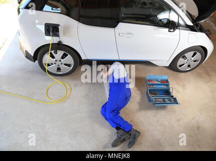 Un meccanico di riparare un condotto elettrico auto presso il garage Foto Stock