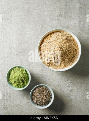 Polvere di maca, i germogli di orzo in polvere e i semi di chia in vari bocce (visto da sopra) Foto Stock