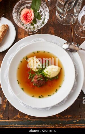 Brodo di manzo con tre diversi condimenti: gnocco di fegato, con gnocchi di semolino e una frittella di trinciato Foto Stock