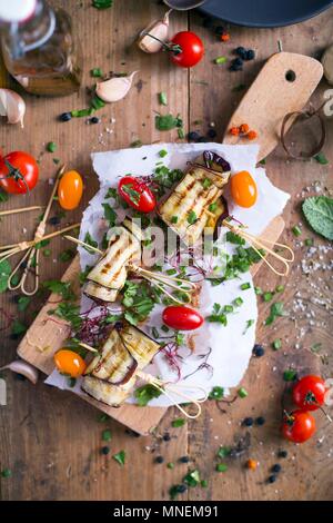 Melanzane grigliate con pomodori e erba cipollina su un tagliere Foto Stock