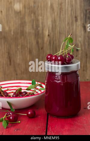 Un vasetto di marmellata di ciliege e le ciliege fresche Foto Stock