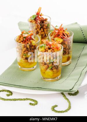 Insalata di lenticchie con le arance e le strisce di prosciutto servito in bicchieri Foto Stock