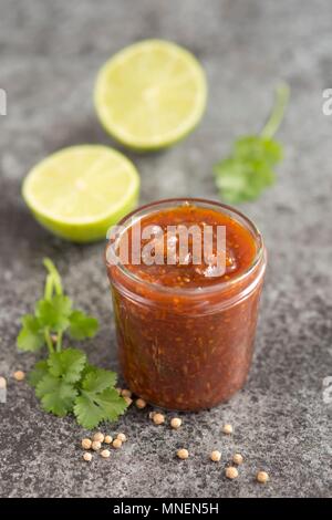 Lime, mango, peperoncino e chutney di coriandolo in un vasetto di vetro Foto Stock