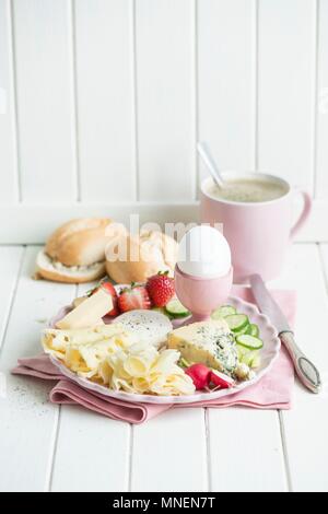 Il formaggio prima colazione con un uovo, ravanelli, fragole, cetriolo, panini e caffè Foto Stock