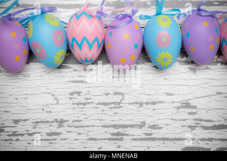 Un gruppo di color pastello le uova di Pasqua su un bianco sullo sfondo di legno Foto Stock