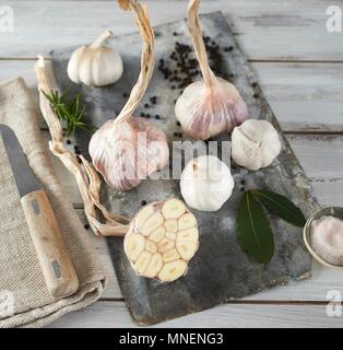 Aglio (viola e bianco) e foglie di alloro su una tavola di legno Foto Stock
