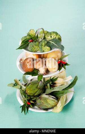 Varie le verdure su una torta di stand Foto Stock
