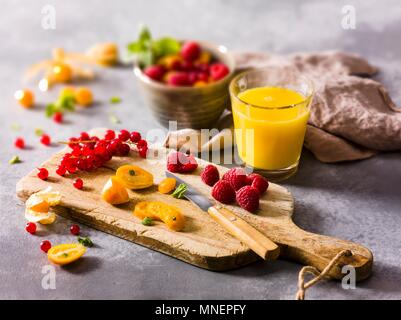 Frutta fresca su di un tagliere e un bicchiere di succo di frutta Foto Stock