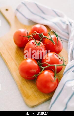 Pomodori sul ramo sul pannello di legno Foto Stock