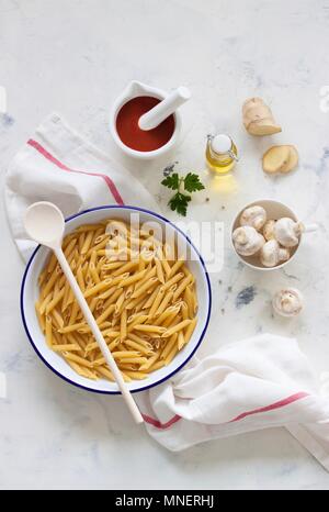 Ingredienti per un piatto di pasta: penne, funghi, setacciato pomodori, olio d'oliva e zenzero Foto Stock