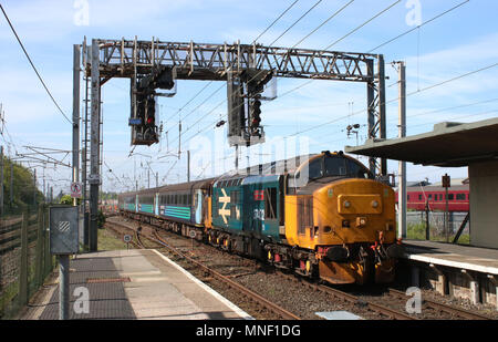 Classe 37 diesel-elettrico in loco BR blu logo grande livrea entrando Carnforth stazione ferroviaria con un treno passeggeri, pullman in livrea DRS. Foto Stock