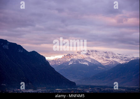 Vista panoramica di Dents du Midi (denti di mezzogiorno), vicino Chablais, Svizzera. Alba il sole illumina distante, cime coperte di neve. Vista dal t Foto Stock