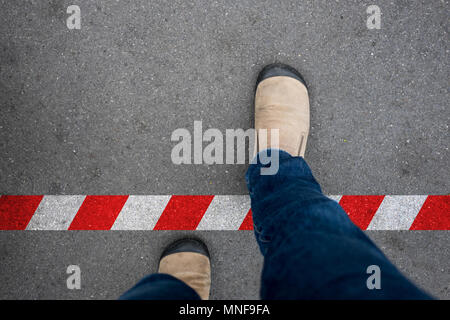 Una camminata attraverso il bianco e il rosso linea alla zona vietata. Rompere la regola oltre il limite. Foto Stock