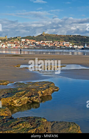 Scarborough del promontorio del castello contro la sabbia e rockpools di South Bay Beach con la bassa marea. Foto Stock