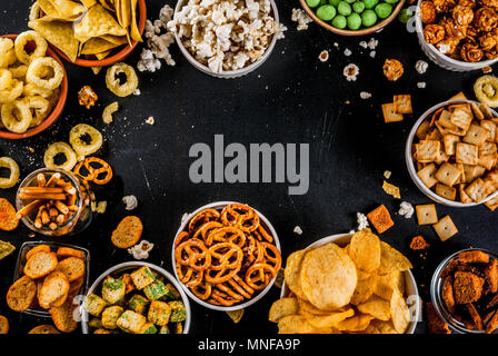 Variazione diversi spuntini malsano di cracker dolci salati di popcorn, tortillas, dadi, cannucce, bretsels, back lavagna spazio di copia Foto Stock