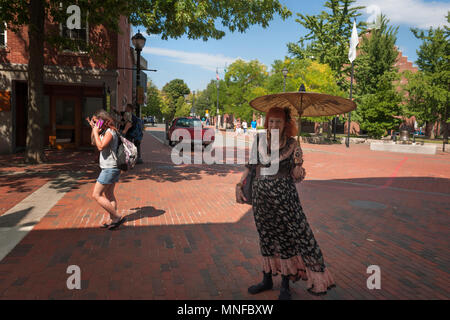 Salem, Massachusetts, STATI UNITI D'America - 14 Settembre 2016: un locale commerciale donna pone per la telecamera mentre lei stessa sfumatura dal sole con la sua parasol mentre su di lui Foto Stock