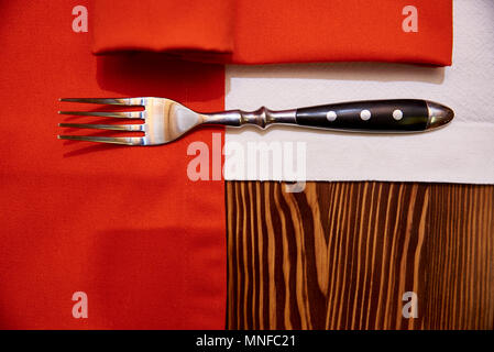 Forcella, tovagliolo bianco e rosso la tovaglia su un tavolo di legno Foto Stock