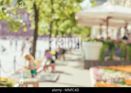 Immagine astratta di un irriconoscibile sagome delle persone che camminano in una strada di città e poggiante su panche in giornata di sole. Urban background moderno. Effetto sfocato Foto Stock