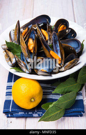 Le cozze al vapore con limone e prezzemolo sul tavolo Foto Stock