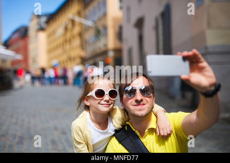 La famiglia felice padre e sua adorabile figlia piccola tenendo selfie con telefono cellulare all'aperto in corrispondenza della strada di Stoccolma, Europa Foto Stock