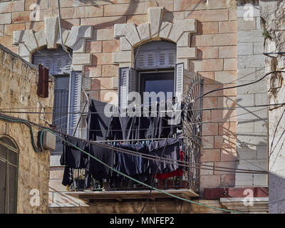 Balcone su un muro di pietra di una vecchia casa con un sacco di lino nero su stendibiancheria, Gerusalemme, Israele. Foto Stock