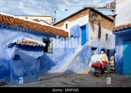 Due donne locali il trasporto delle borse della spesa a piedi attorno a Chefchaouen Foto Stock