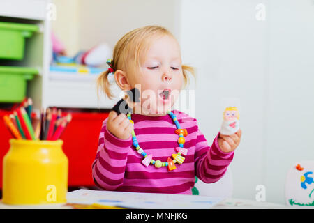 Adorabile ragazza toddler giocando con il dito fantoccio a casa o asilo nido Foto Stock