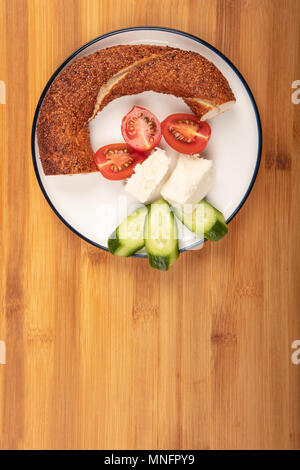 La prima colazione con il formaggio feta, simit, cetriolo, e ciliegia tomoto isolato su sfondo di legno vista superiore Foto Stock