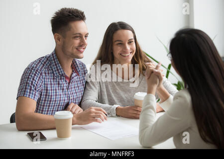 Coppia sorridente parlando di agente immobiliare Foto Stock