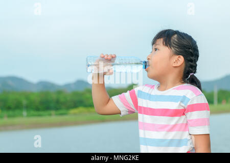 Bambino di bere acqua pura in natura nei pressi del lago, concetto sano Foto Stock