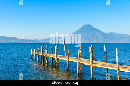 Il molo di legno al lago Atitlan sulla spiaggia in Panajachel, Guatemala. Con un bellissimo paesaggio paesaggio di vulcani Toliman, Atitlan e San Pedro in Foto Stock