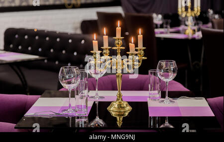 Bicchieri e un candelabro su un tavolo di vetro in un ristorante. Ambiente romantico Foto Stock