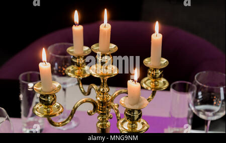 Bicchieri e un candelabro su un tavolo di vetro in un ristorante. Ambiente romantico Foto Stock