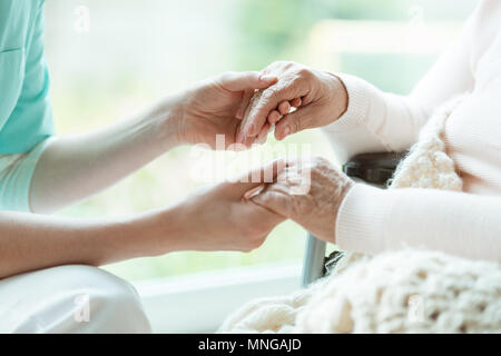 Foto di infermiere tenendo la sua donna mani del paziente con unghie verniciate Foto Stock