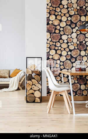 Calda sala da pranzo decor ispirato autunno bosco con arredamento semplice, legna da ardere e registri di sfondo Foto Stock