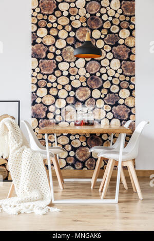 Morbidi tessuti e carta da parati di registro nella suggestiva sala da pranzo con arredamento scandinavo, bianco e sedie di legno tavolo comunale Foto Stock