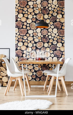 Design in legno dettagli in caldo inverno interno della sala da pranzo con parete bianca, tavolo comunale e vino decantatori Foto Stock