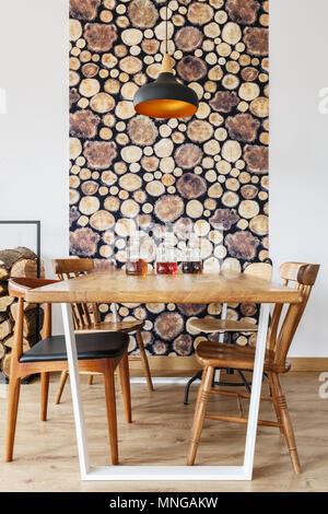 Tavolo da pranzo in legno e sedie e parete decorazione moderna in una luminosa sala da pranzo con design naturale Foto Stock