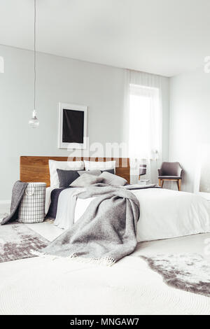 Poster nero su bianco parete con copia spazio sopra il letto king size nella camera da letto luminoso interno con sedia e finestra Foto Stock