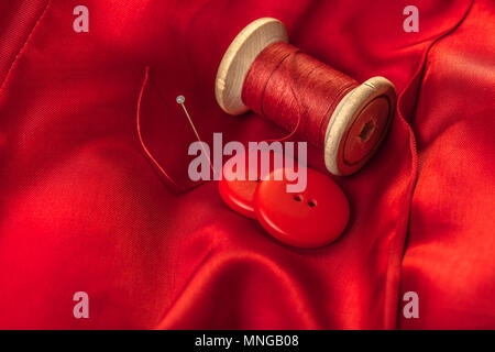 Filo rosso con pulsanti sullo sfondo di tessuto di rivestimento Foto Stock