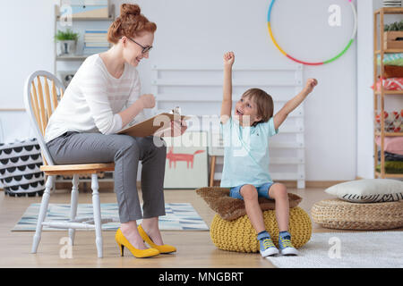 Ragazzo giovane sentirsi felice perché ha fatto progressi in lezioni di parlato durante la riunione con logopedista Foto Stock