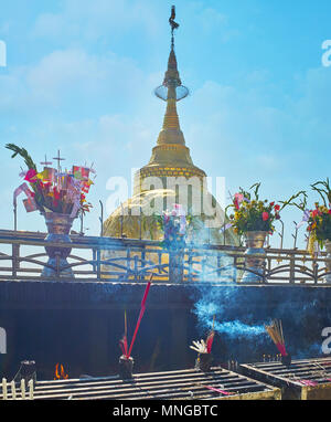 L'altare esterno con fumi di bastoncini di incenso e candele accese nella parte anteriore del htee Kyite Yoe Pagoda costruita sulla sommità del gigantesco masso di granito sul summi Foto Stock