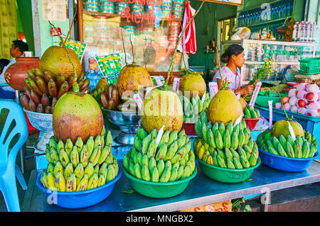 KYAIKTIYO, MYANMAR - Febbraio 16, 2018: le belle composizioni di frutta delle banane verdi e noci di cocco da bere in stallo del mercato del Golden Rock compl Foto Stock