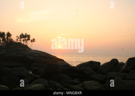 Impostazione di Sun sulle rocce a Palolem Beach, Goa, India Foto Stock