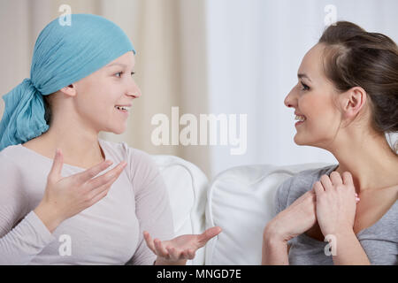 Cancro giovane donna che indossa velo, parlando con un amico Foto Stock