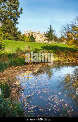 Batsworth Casa Vittoriana mock Tudor stile country house a Batsford Park, Moreton-in-Marsh, Gloucestershire in una giornata autunnale di riflessioni in un lago Foto Stock