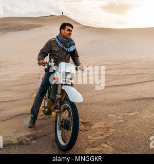 Dasht-e-lut, Iran - 25 Aprile 2018: Editoriale illustrativa di un giovane uomo su una motocicletta che pongono a Dasht-e-lut, un grande deserto di sale si trova in pr Foto Stock