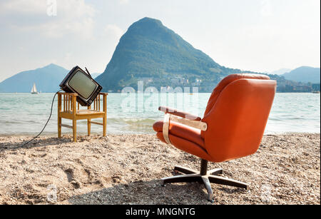 Arredamento Vintage sulla riva del lago, poltrona e televisore. Vista del lago Ceresio e il Monte San Salvatore Foto Stock