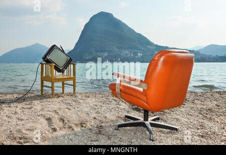 Arredamento Vintage sulla riva del lago, poltrona e televisore. Vista del lago Ceresio e il Monte San Salvatore Foto Stock