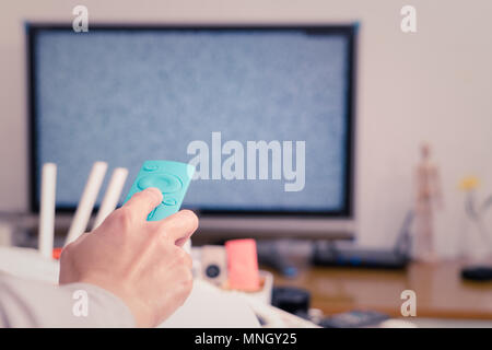 Una donna a tenere in mano il telecomando del TV box nel soggiorno, la schermata vuota TV Foto Stock